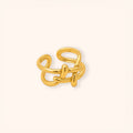A 18K gold-toned abstract interlocking ring with a polished finish, centered on a clean off-white background.
