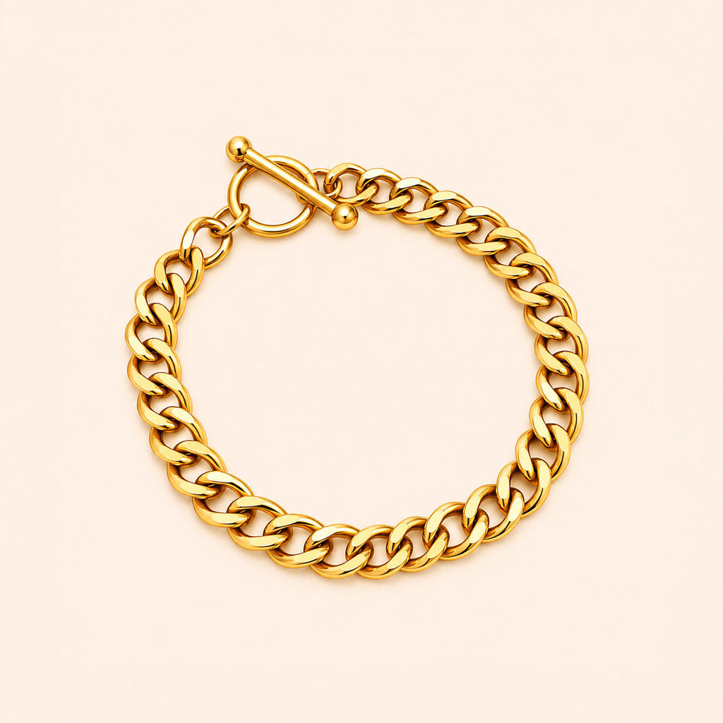 A polished yellow gold curb link bracelet with a toggle clasp, displayed on a light cream background.