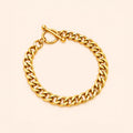 A polished yellow gold curb link bracelet with a toggle clasp, displayed on a light cream background.