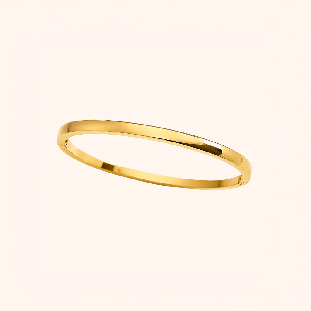 A minimalist, polished yellow gold bangle bracelet shown on a clean, solid, warm off-white background.