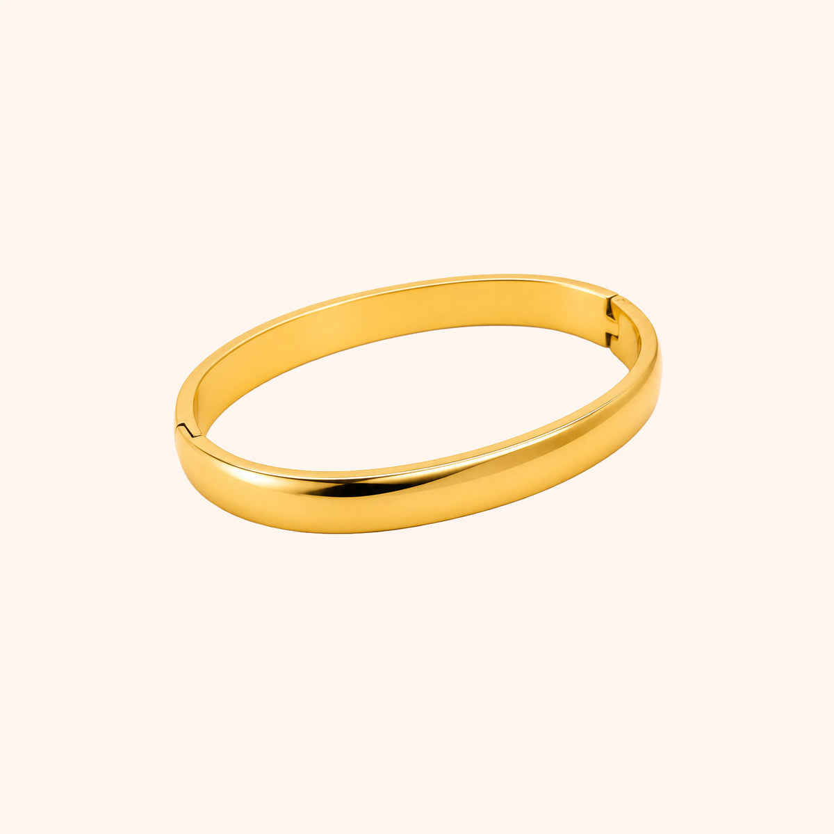 A polished gold bangle bracelet with a smooth, rounded oval shape, displayed on a clean, solid off-white background.