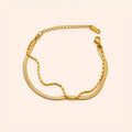 A gold-tone chain bracelet with a textured snake-link style chain, a beaded chain section, and an adjustable lobster clasp, displayed on a light cream background.