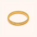 A gold-colored segmented bangle bracelet with a textured, ribbed design, displayed on a clean off-white background.