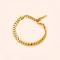 A gold-toned metal chain bracelet with a curb-style link design, displayed on a light cream background.