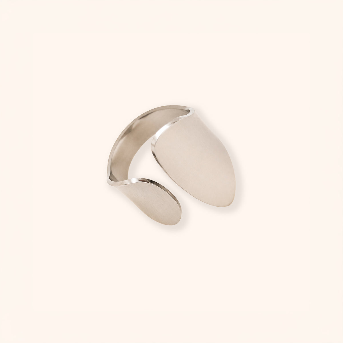 A minimalist silver-toned open cuff ring with a smooth, matte finish and a polished reflective edge, displayed on a clean, solid off-white background.